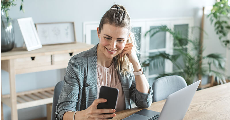 Woman at home office smiling at phone