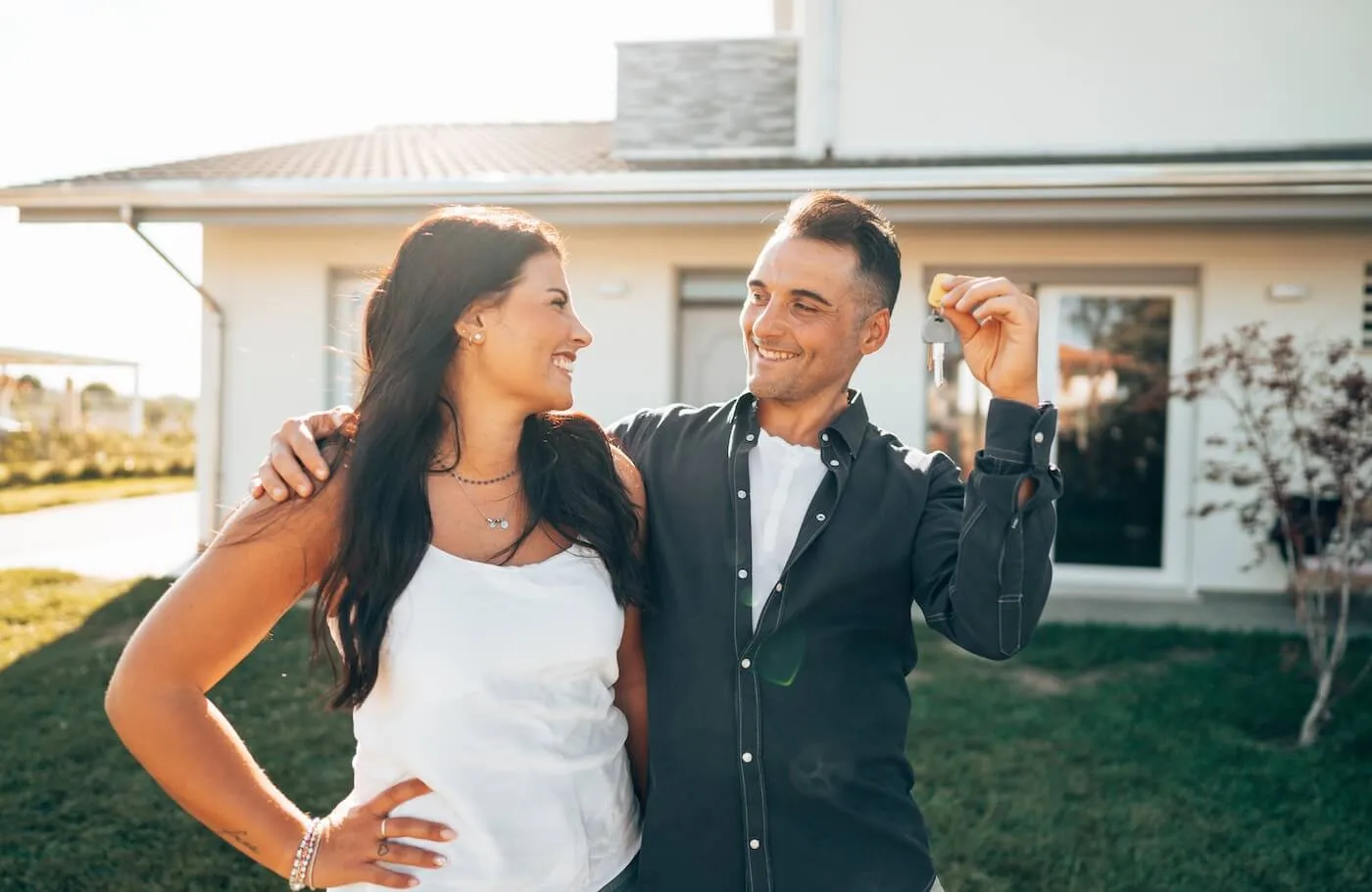 Happy couple standing outside the house and holding the house keys
