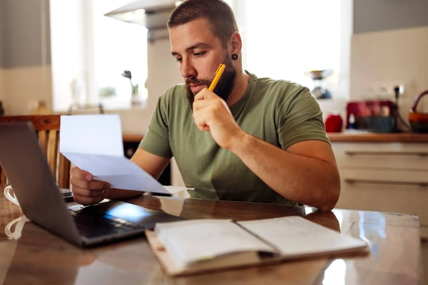 Concerned man reviewing a bill while using his laptop at home