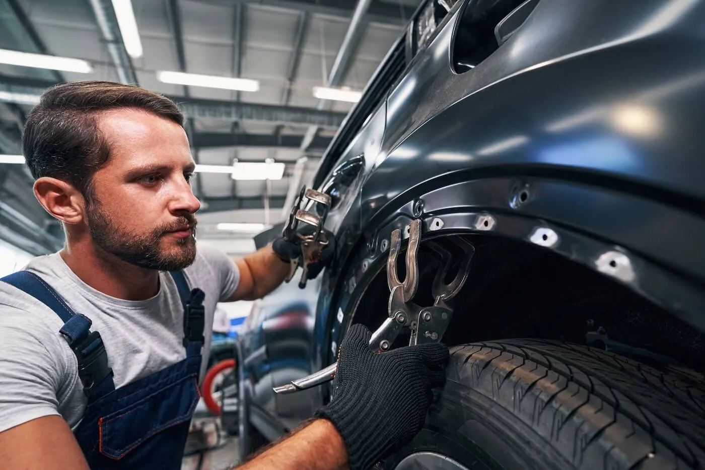 Male mechanic adjusting a screw clamp on a car body