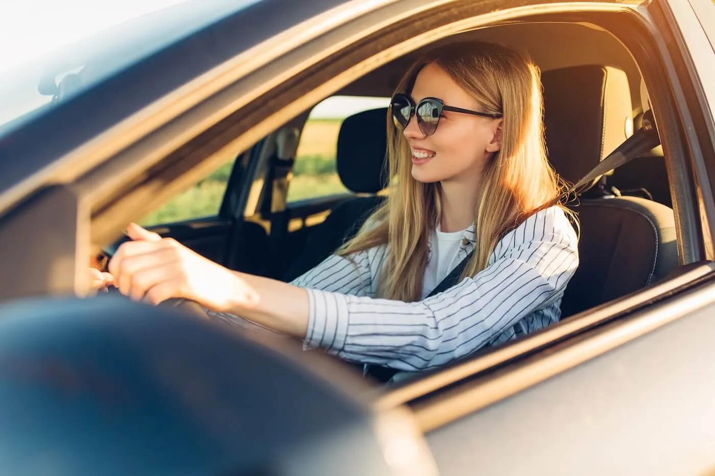 Smiling young woman wearing sunglasses driving a car