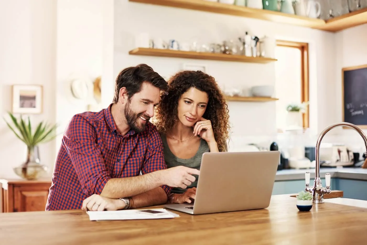 Happy couple using a laptop together on a kitchen countertop