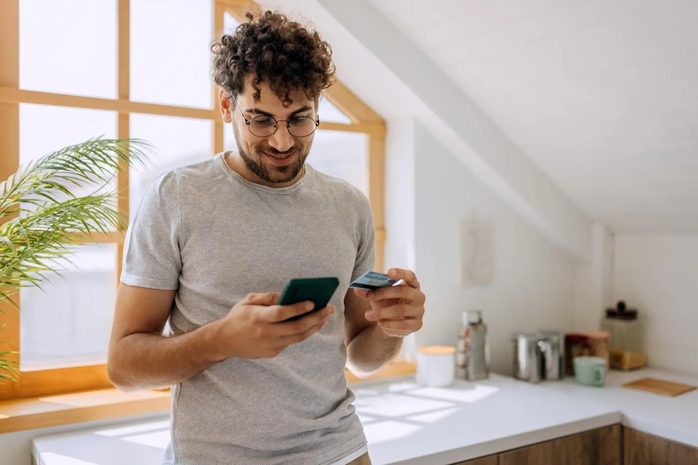 Smiling man checking his smartphone while holding a credit card