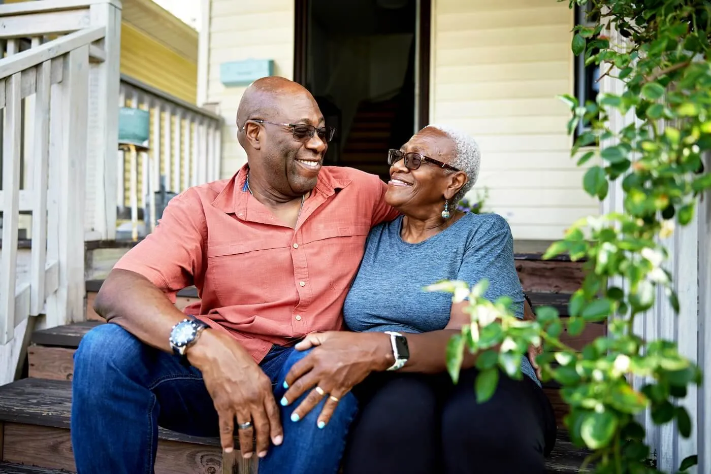 Happy senior couple sitting on the porch of their house, embracing each other