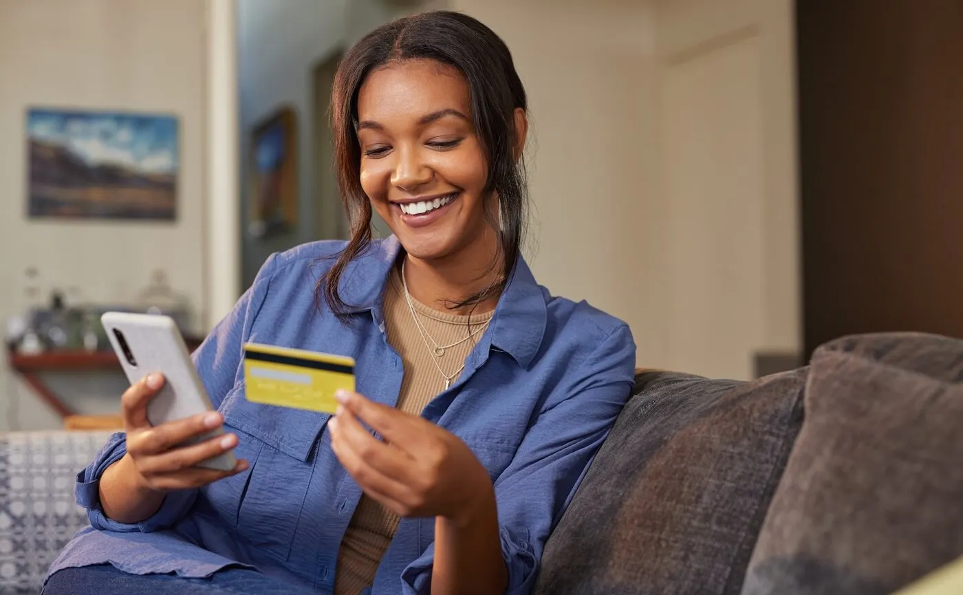 Smiling woman using her credit card via smartphone