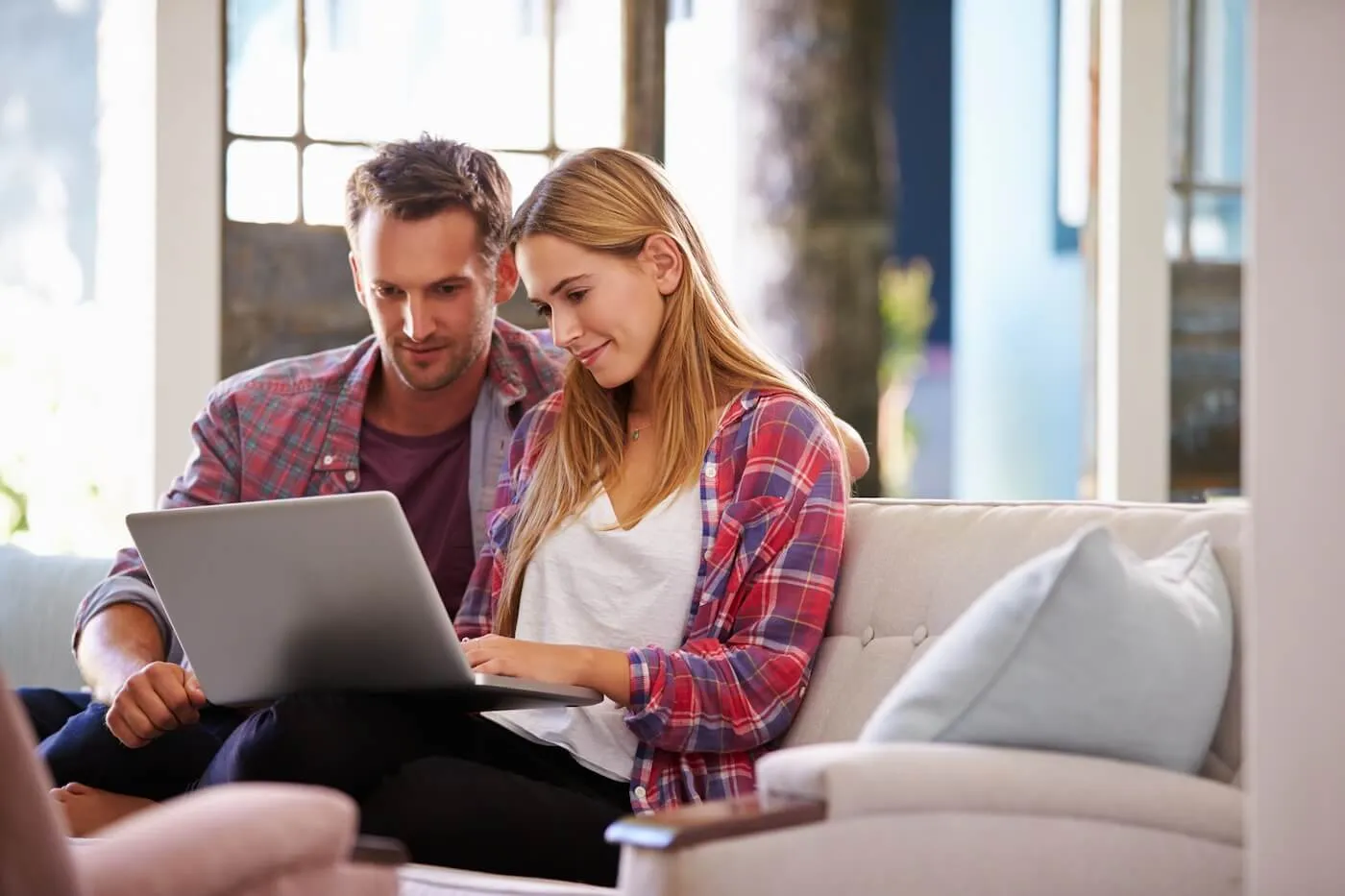 Young couple sitting on a sofa with an open laptop