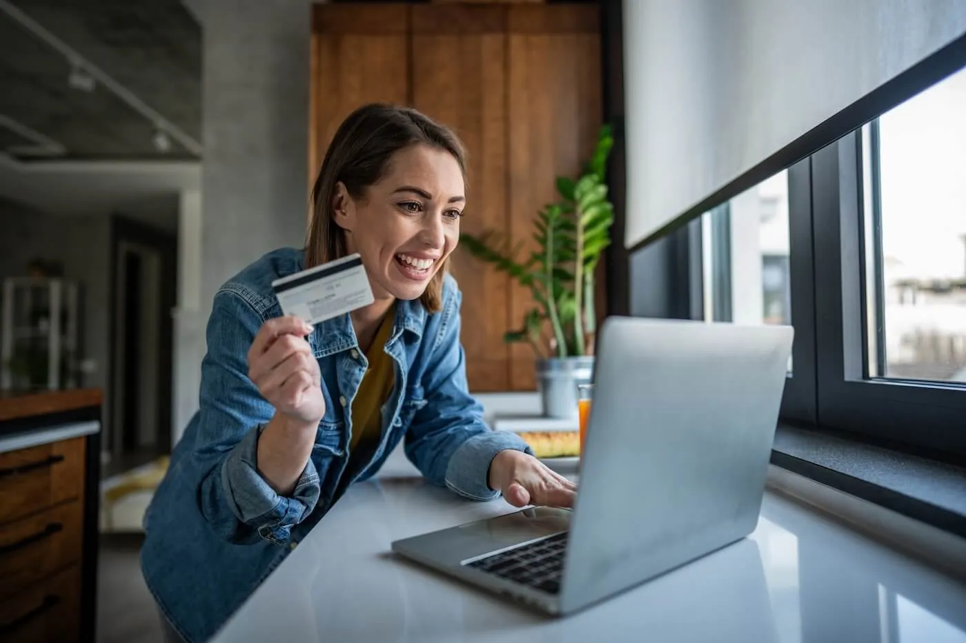 Smiling young woman using her credit card and a laptop