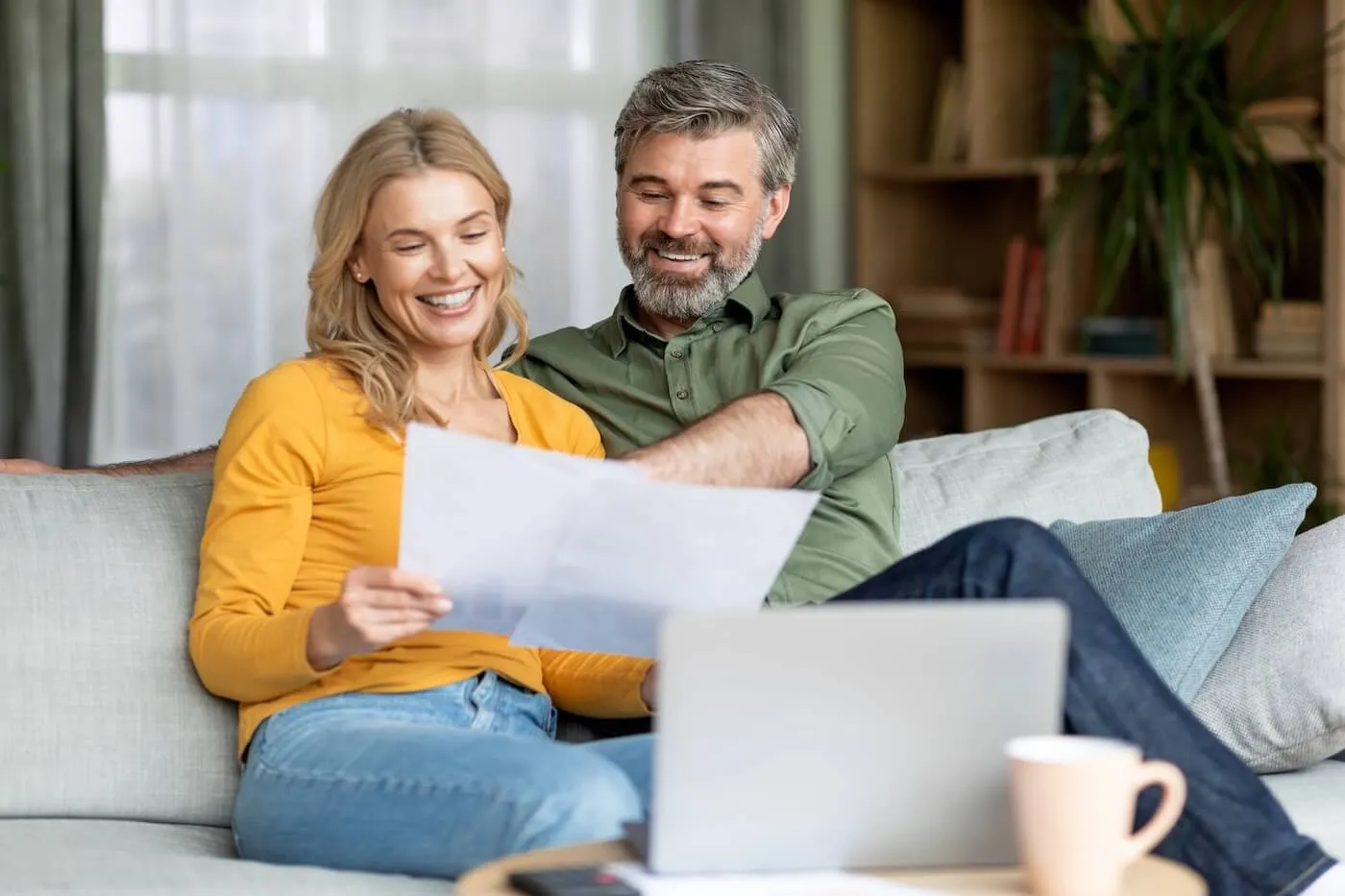 Happy couple reviewing printed documents at home