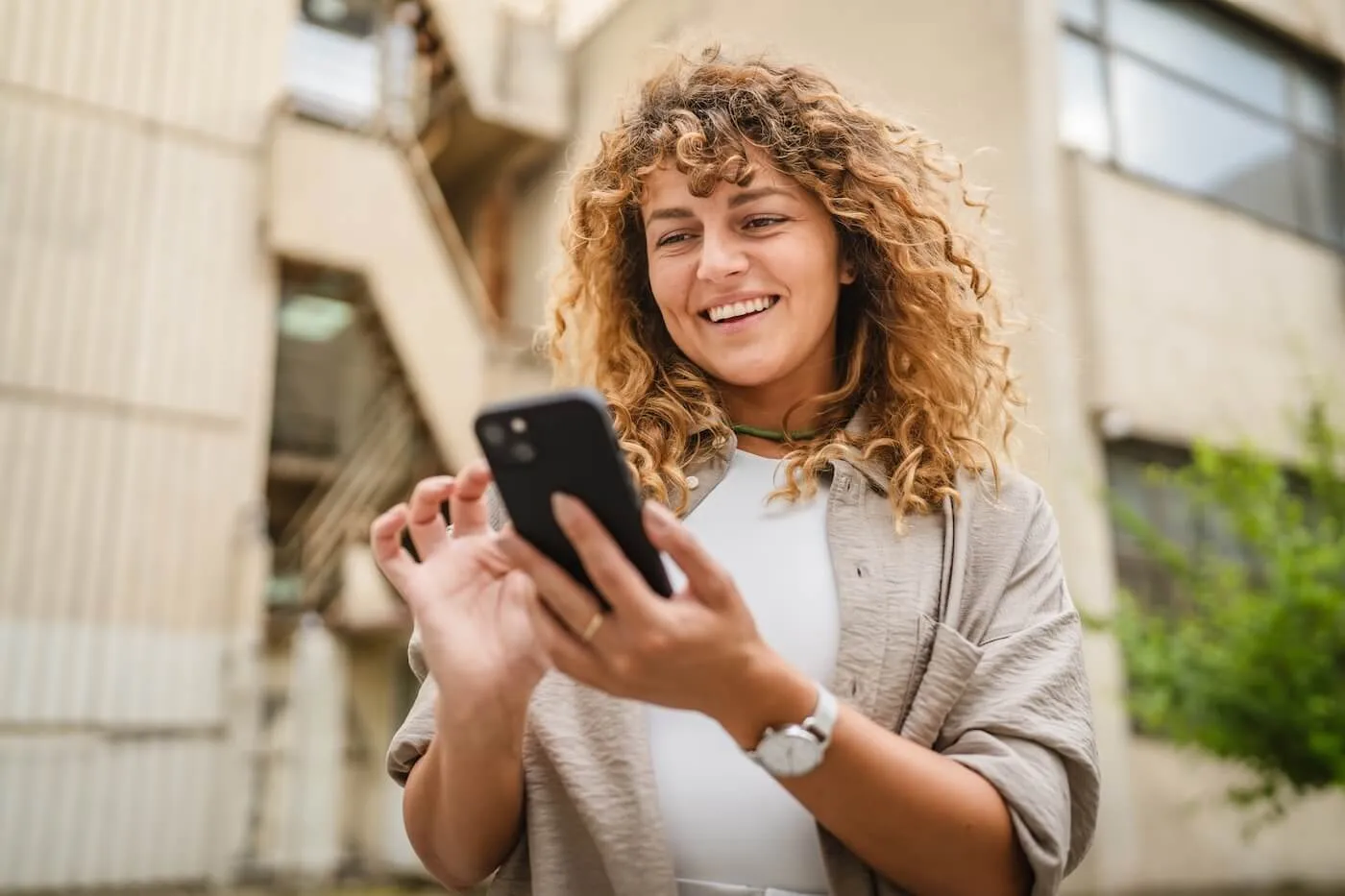 Smiling young woman using her smartphone outdoors