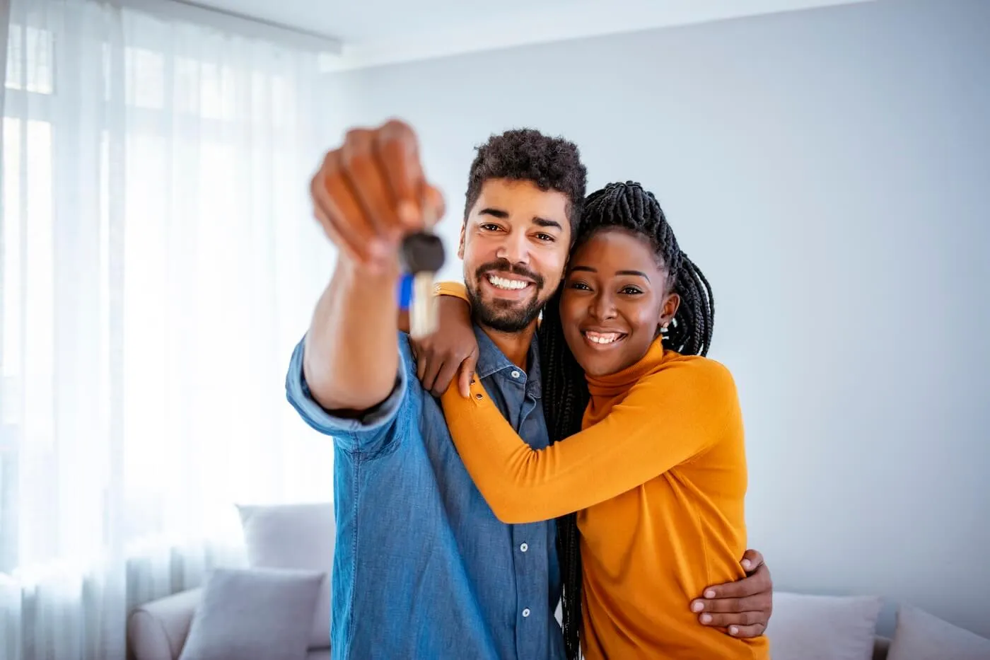 A happy young couple hugging each other while the man holds the house keys