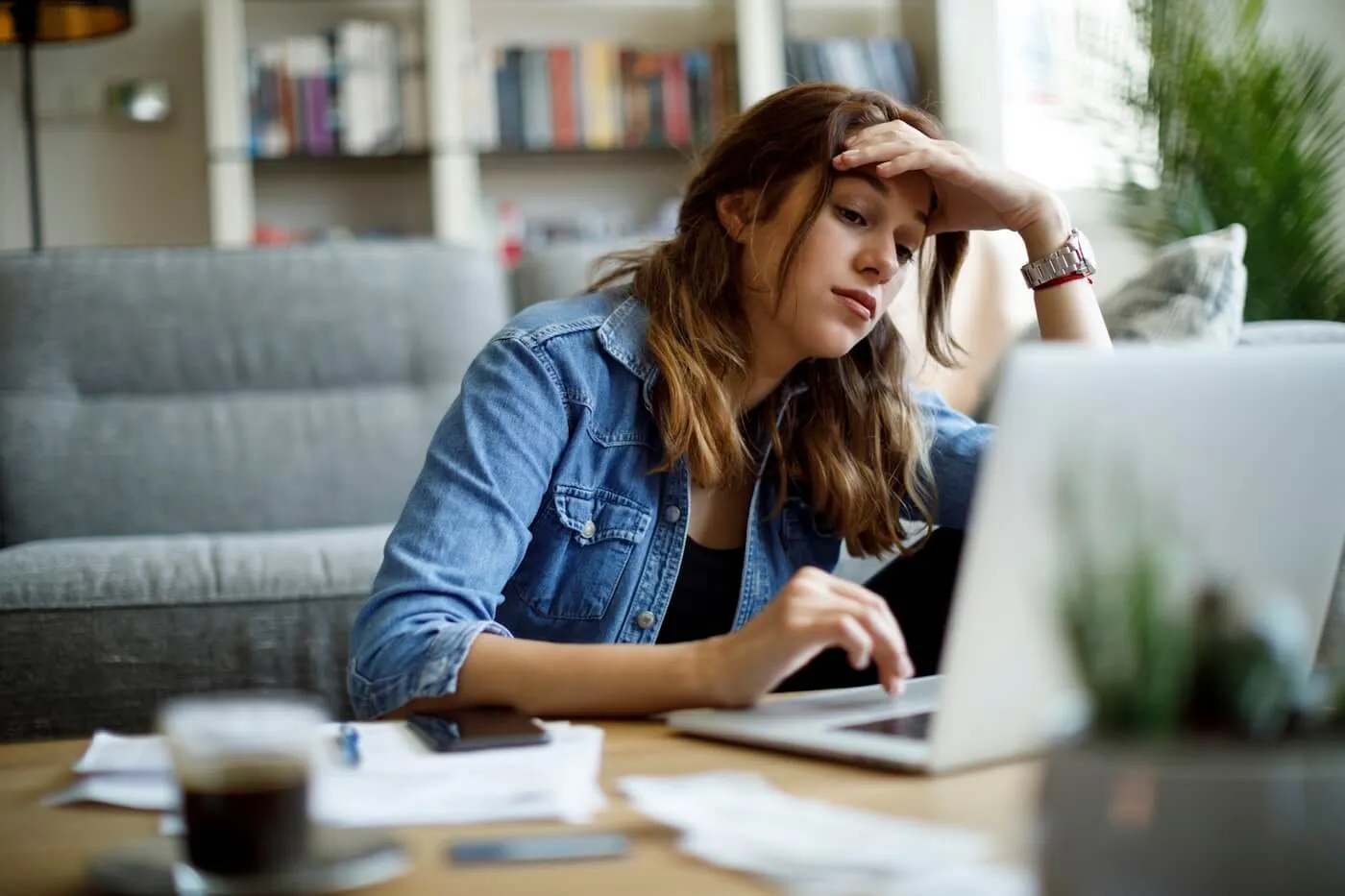 Concerned young woman using her laptop in the living room