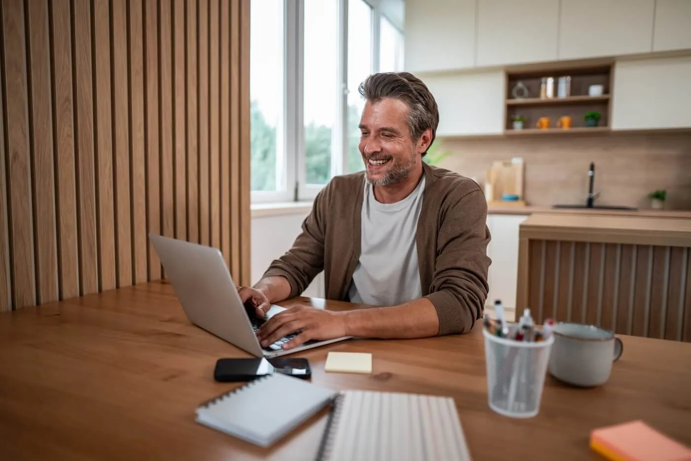 Smiling mature man using his laptop at home