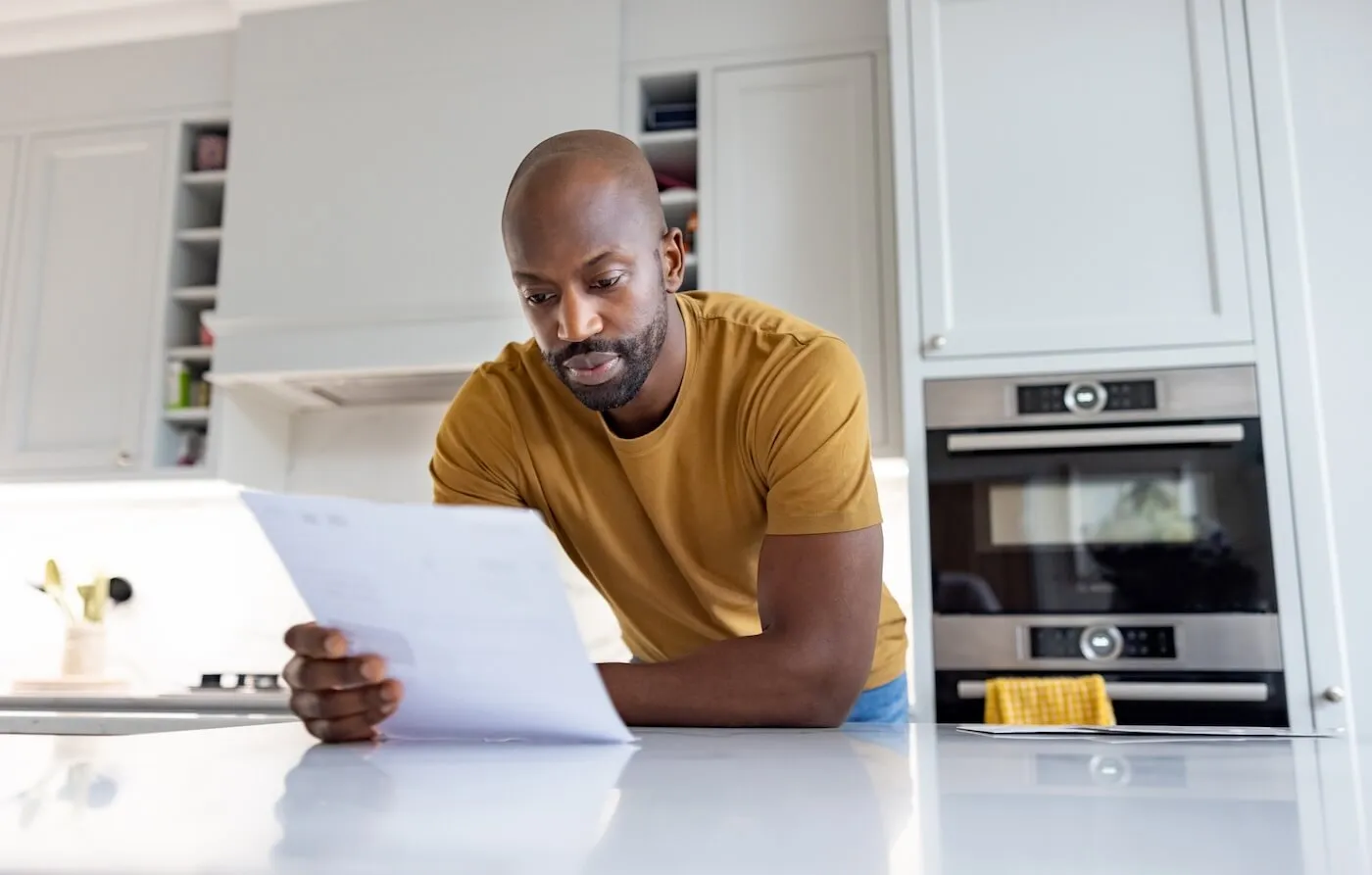 Focused man reviewing a bill in the kitchen