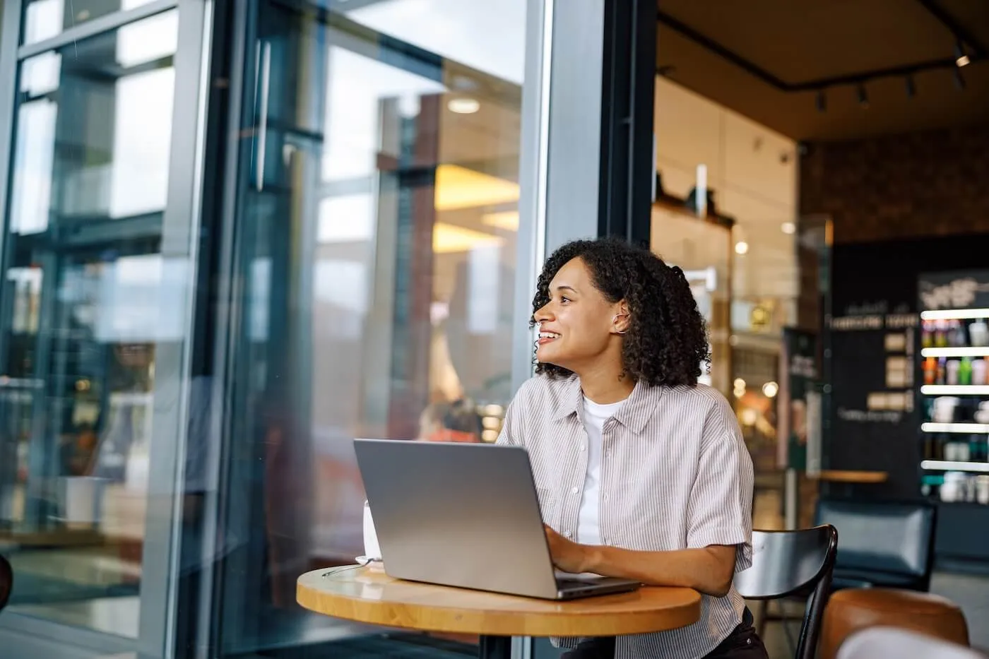 Smiling woman working on a laptop at an outdoor café