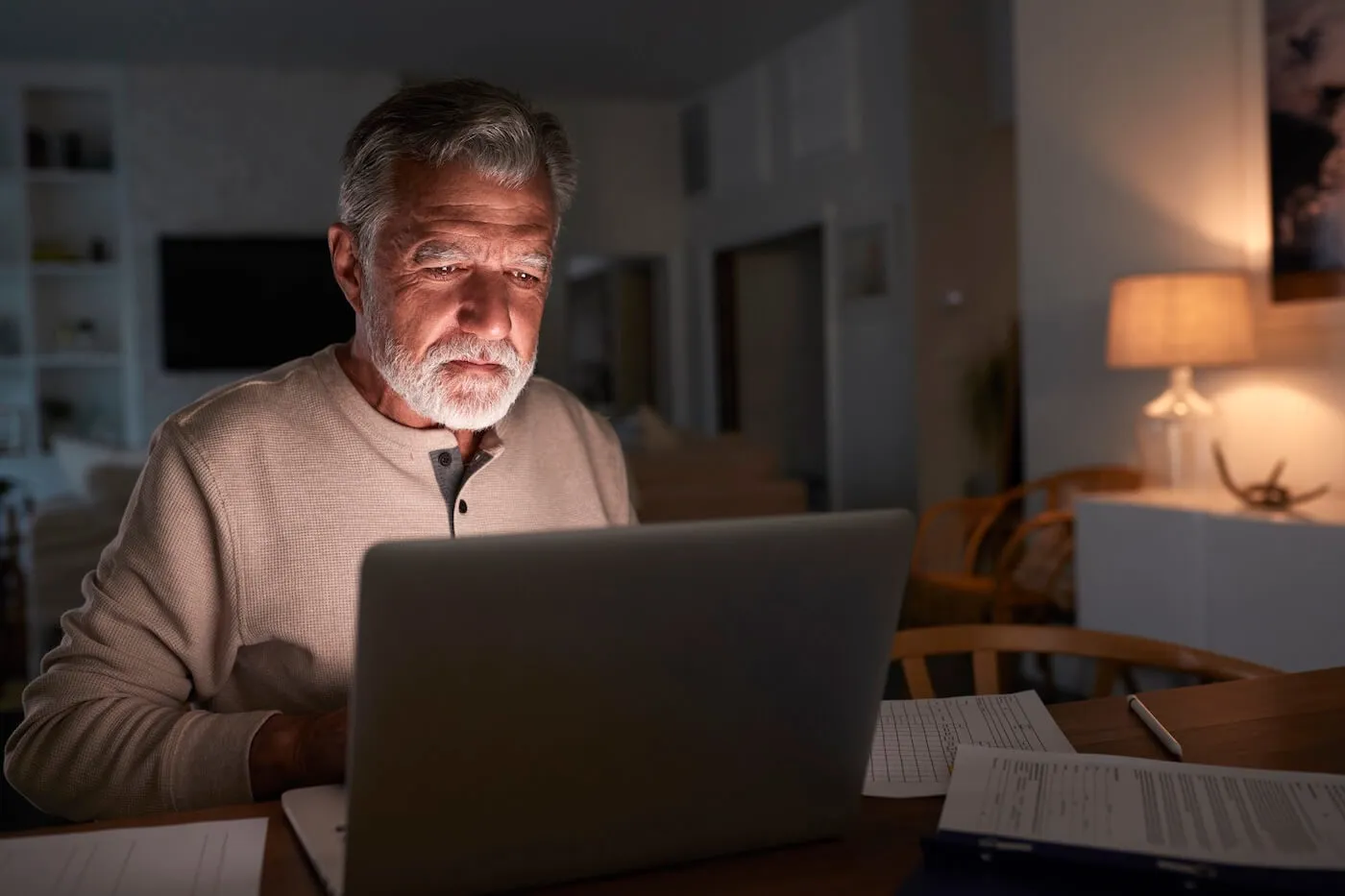 Focused senior man using laptop at home in the evening