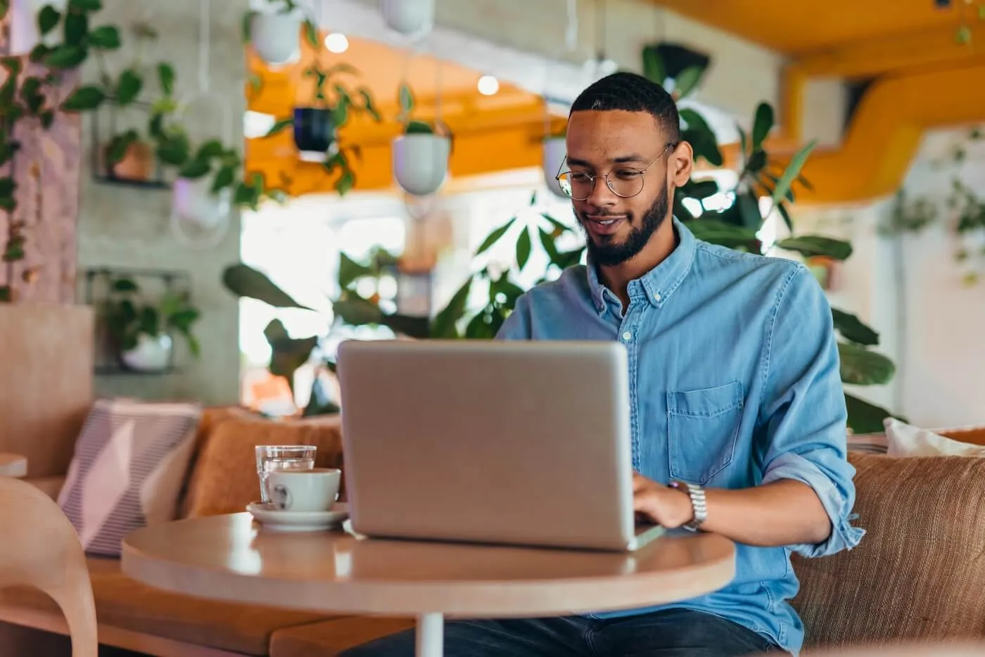 Smiling young man using his laptop in the cafe