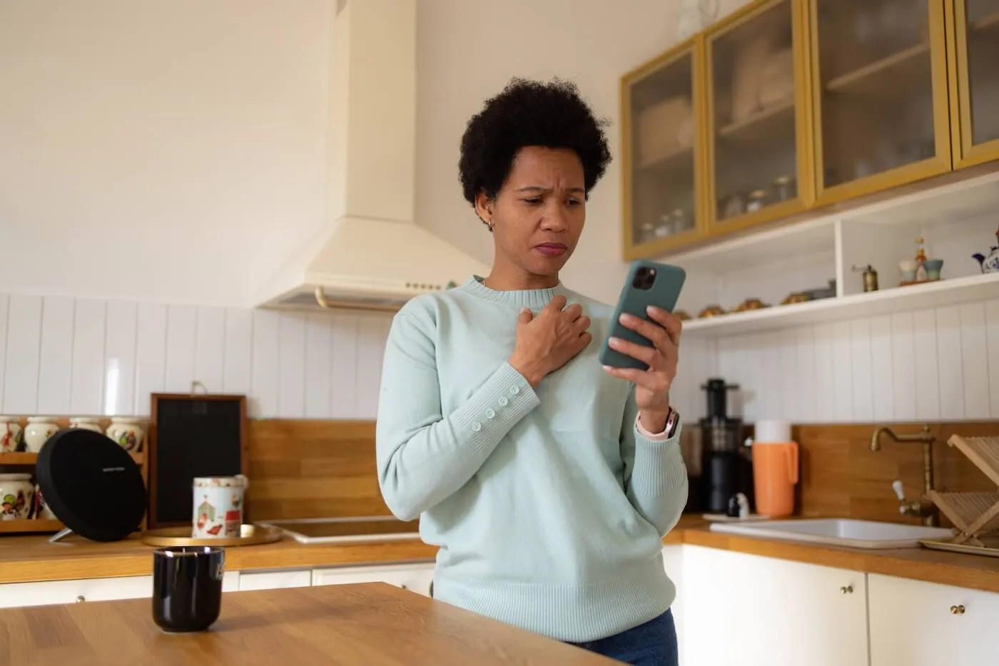 Concerned mature woman using her smartphone in a kitchen