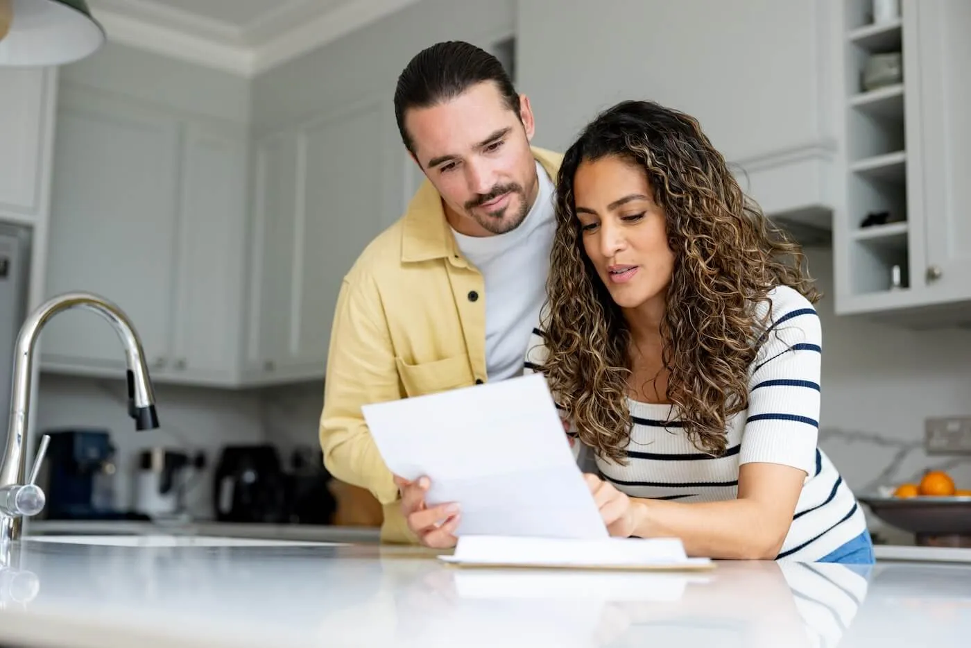Young couple reading a letter together in the kitchen