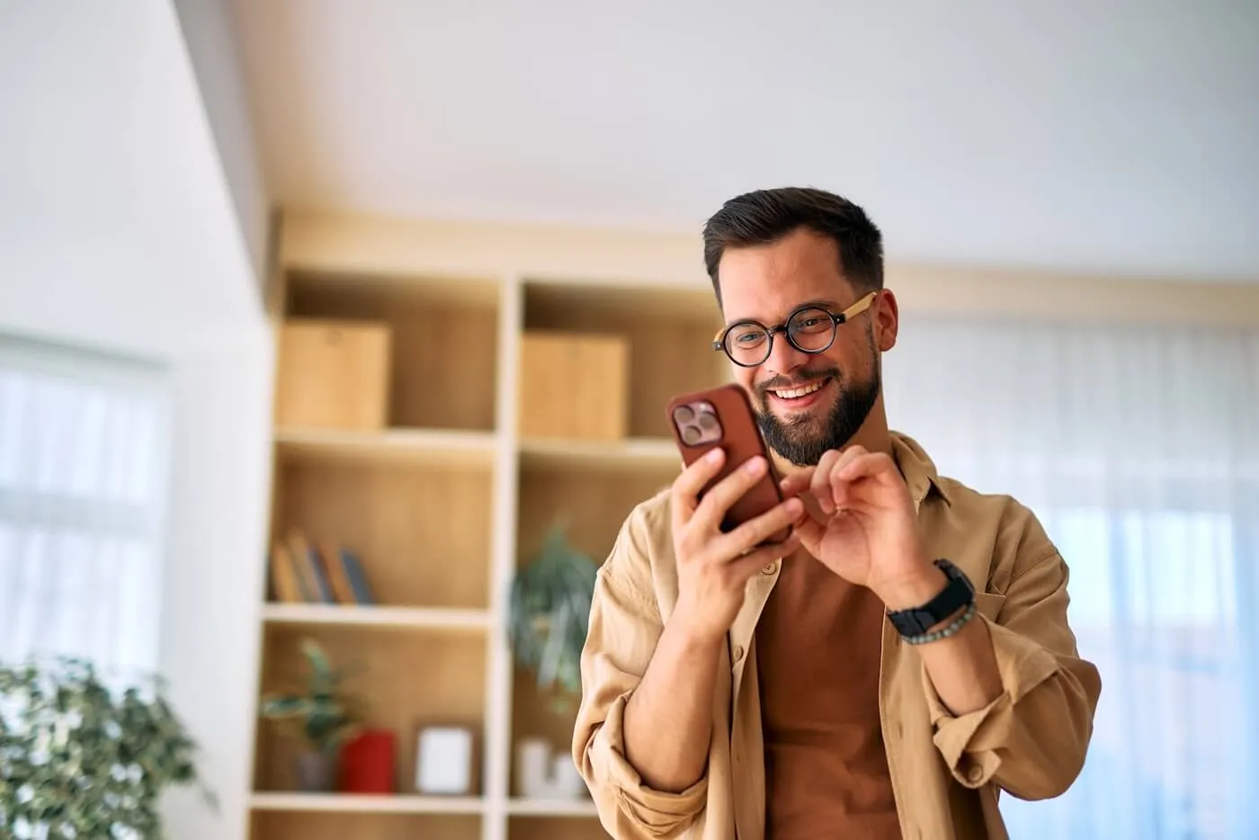 Smiling young man using his smartphone at home