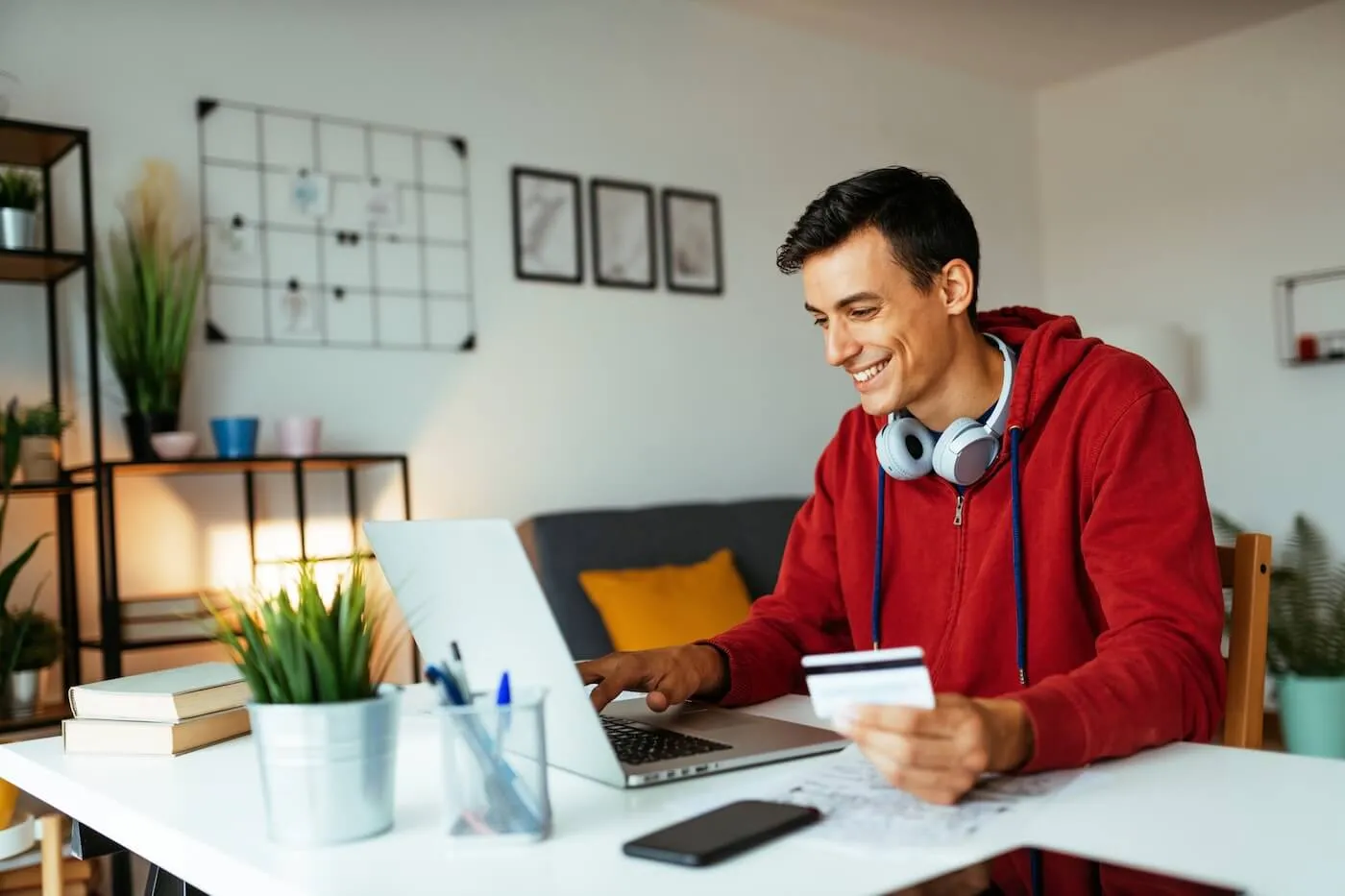 Smiling young man paying bills online in his home office