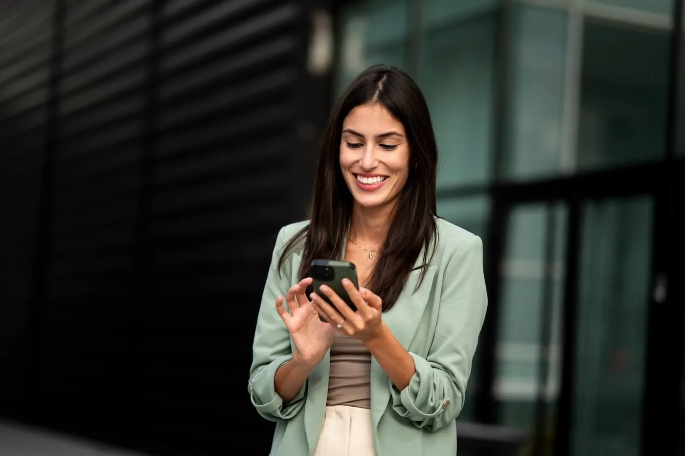 Smiling businesswoman checking her smartphone outdoors