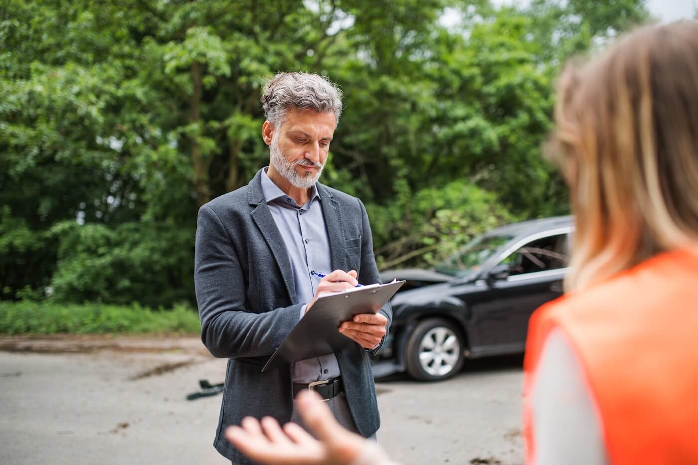 A person inspecting a car damaged by a large tree branch, determining who is responsible if a tree falls on my car