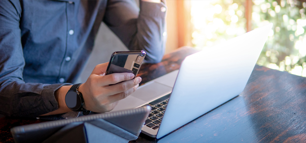 Man looking at smartphone and laptop