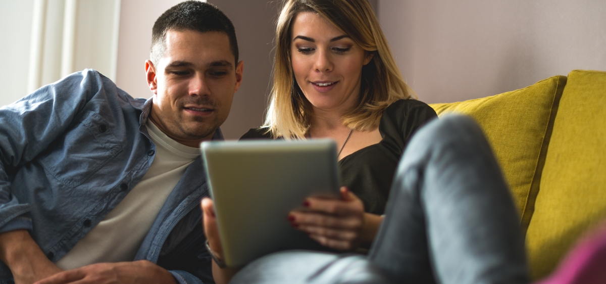 man and woman looking at device on sofa