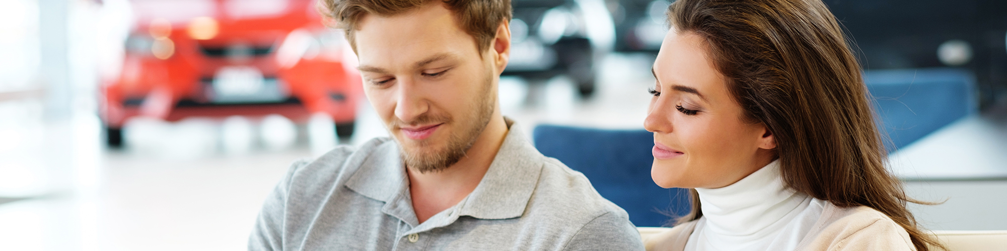 Young couple looking at tablet in car dealership