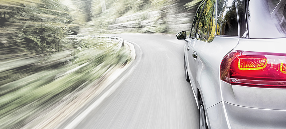 SUV driving on road with foliage alongside road