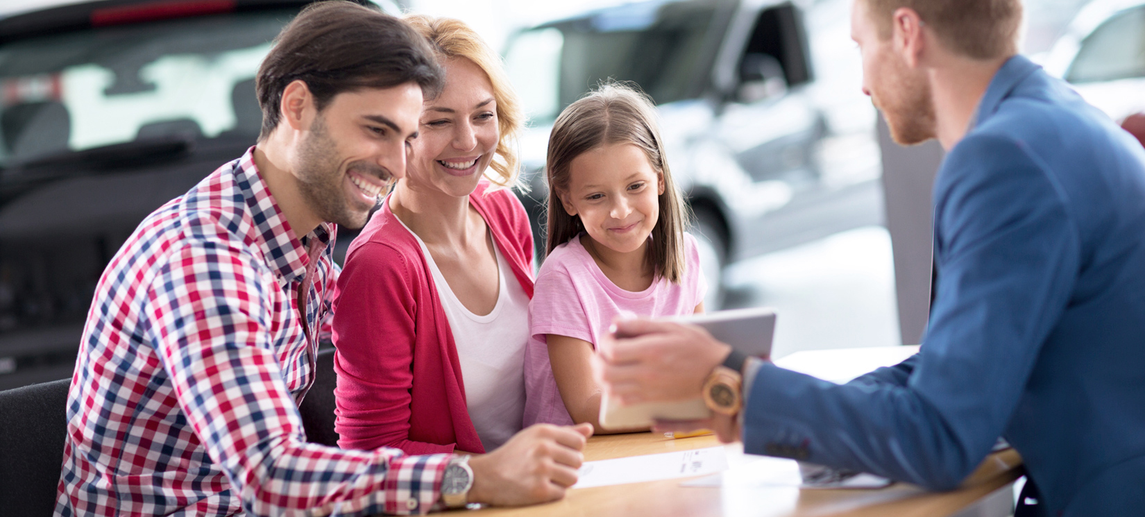 Family looking at tablet in car dealership