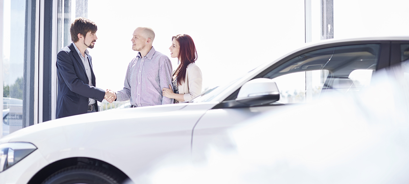 Car dealer with couple in showroom