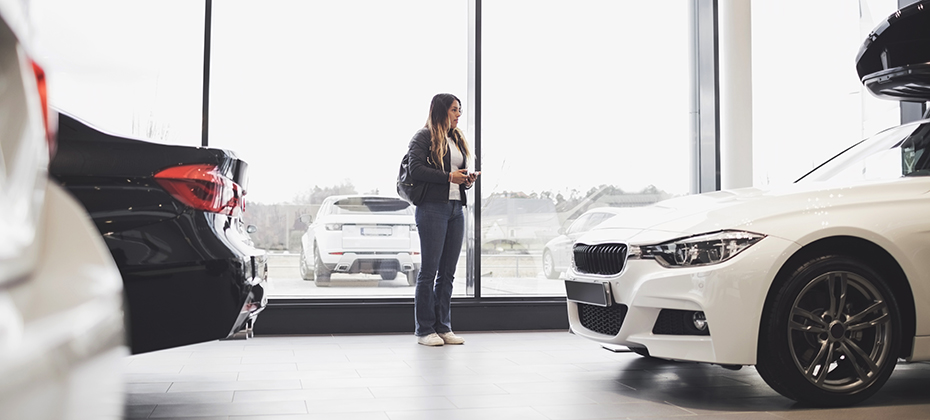 Young woman standing against glass window at car showroom