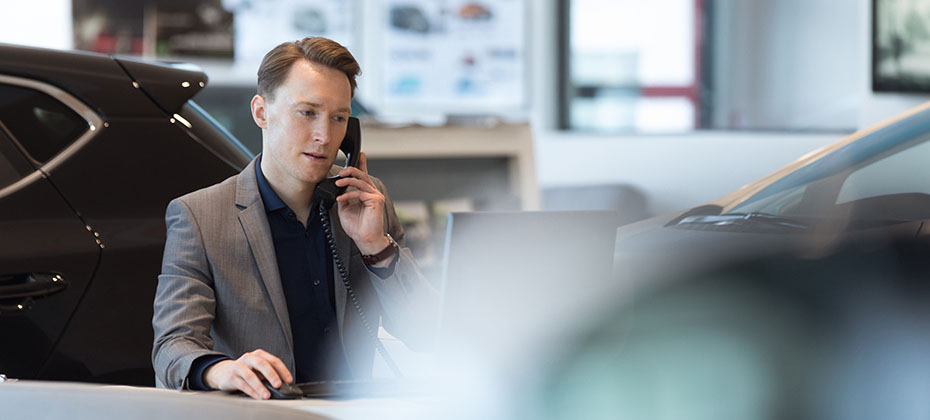 Car salesperson talking on landline phone