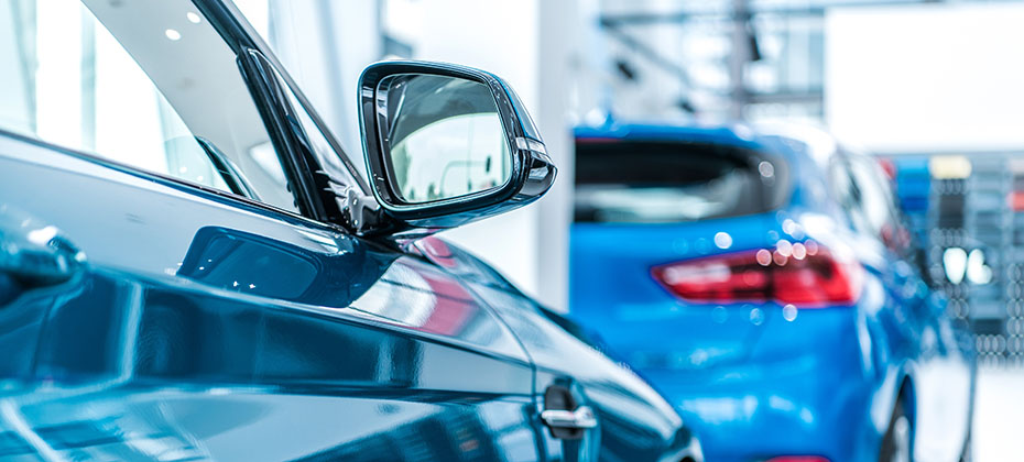 two blue cars parked in tandem in an automotive showroom