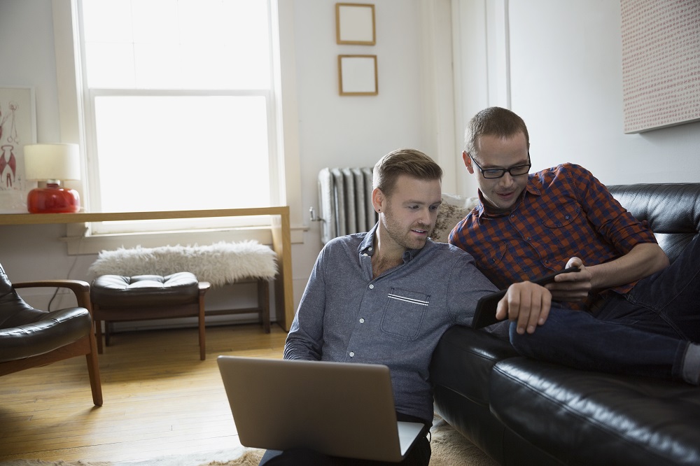 Homosexual couple using technology in living room