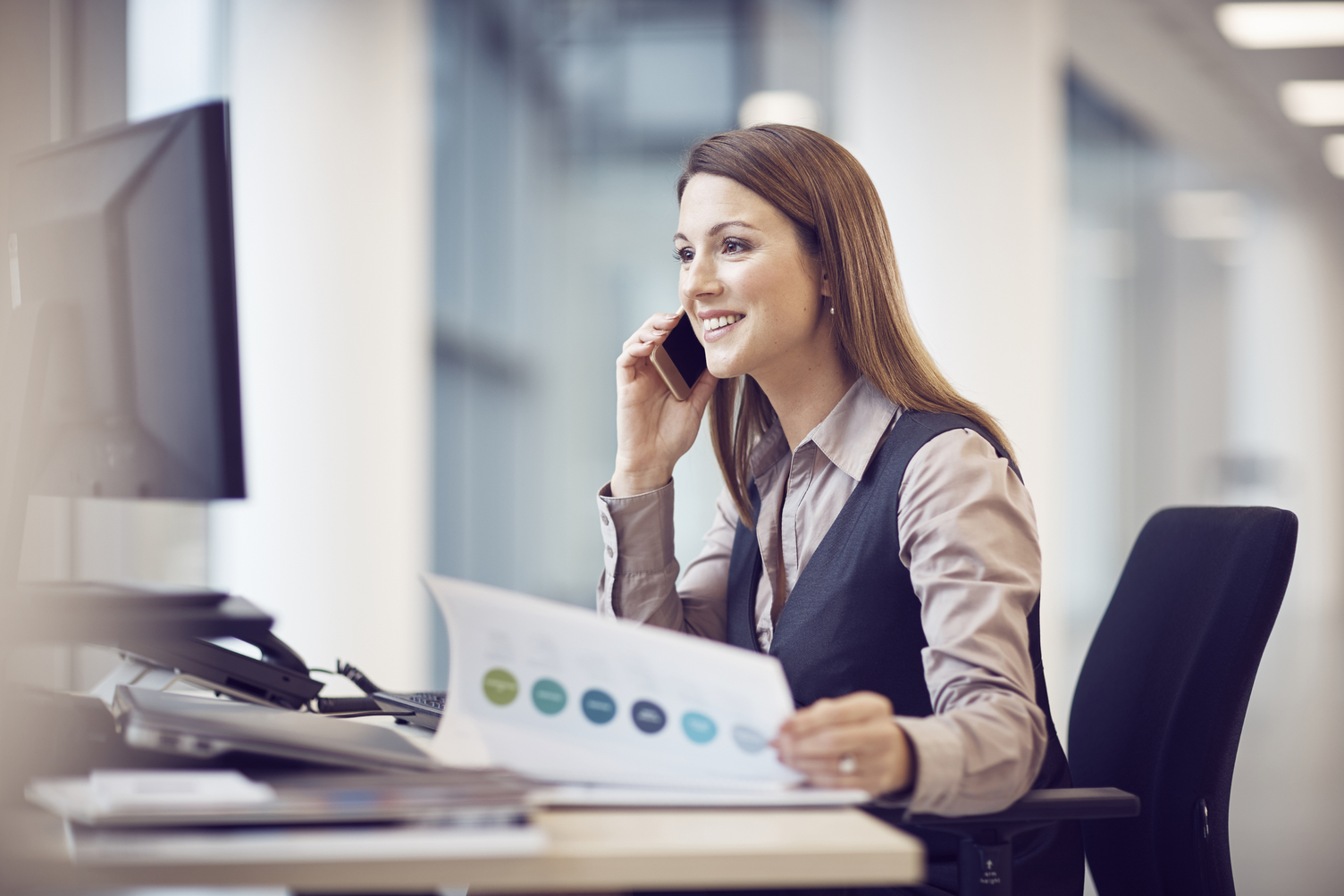 Woman on phone holding paperwork.