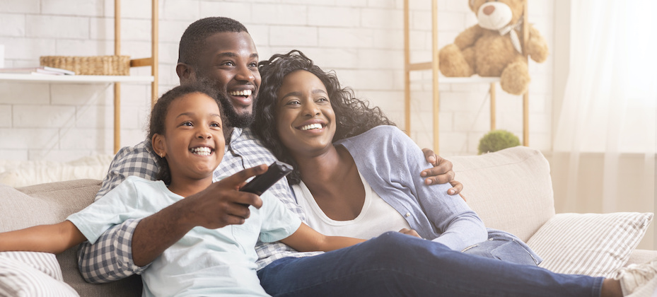 Happy Black family relaxing and watching TV at home
