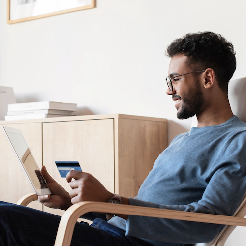 Man using digital tablet and holding credit card at home
