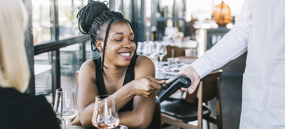 Young, Black woman paying with credit card at the restaurant