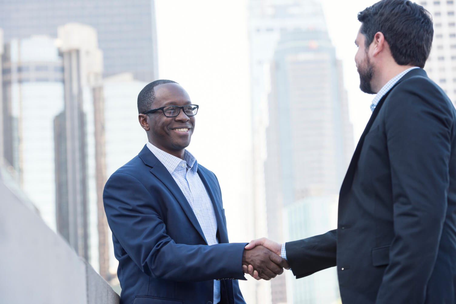 Black man in a suit is shaking hands with a white man in a suit