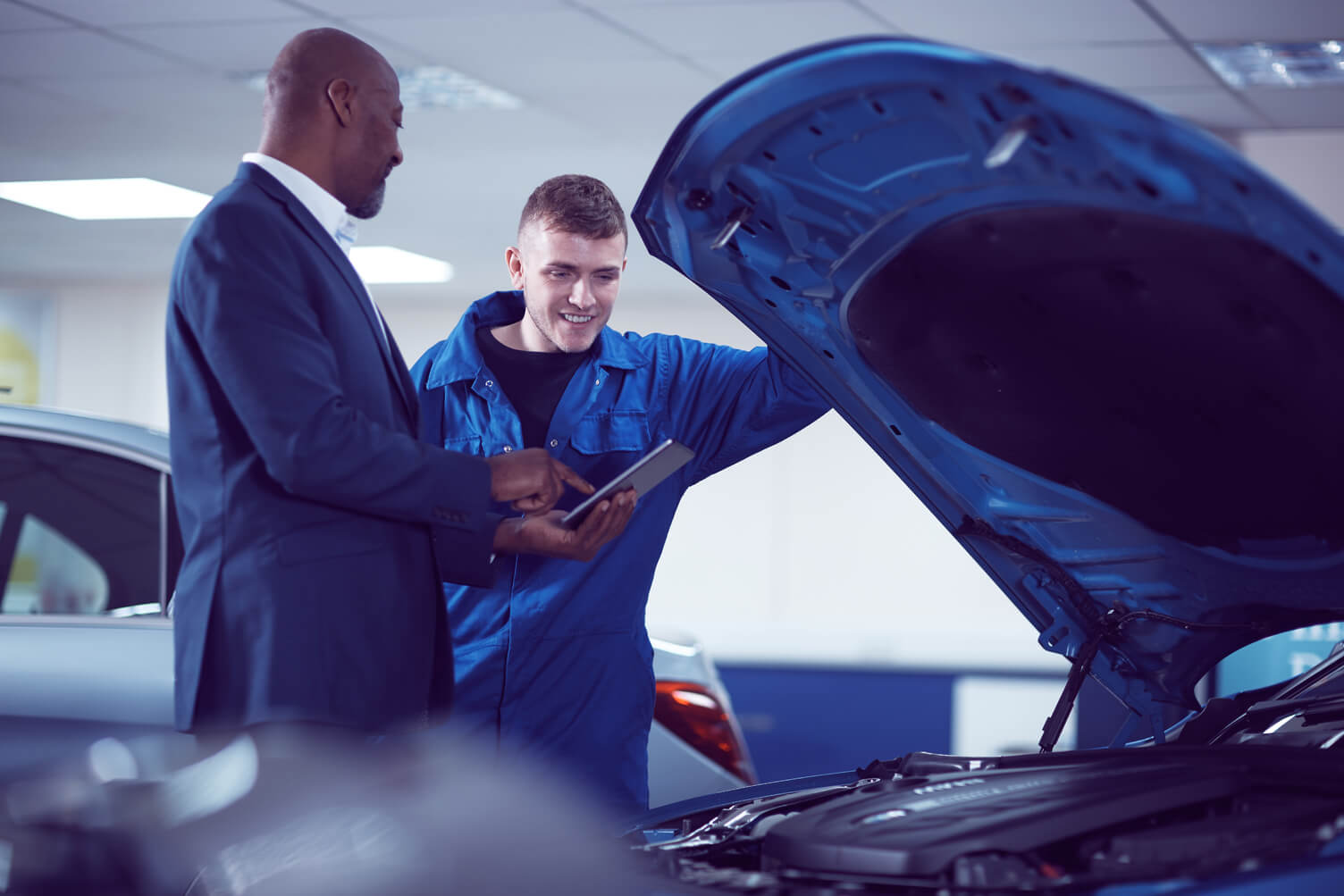 Two men looking under the hood of a car