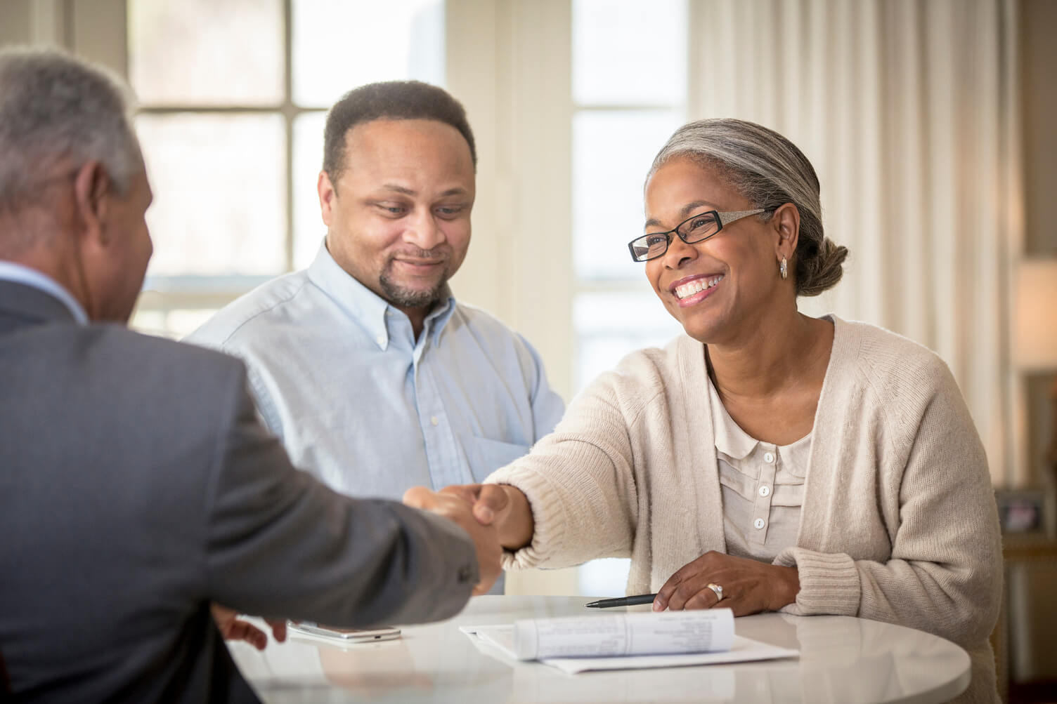 Husband and wife shaking hands with a business man