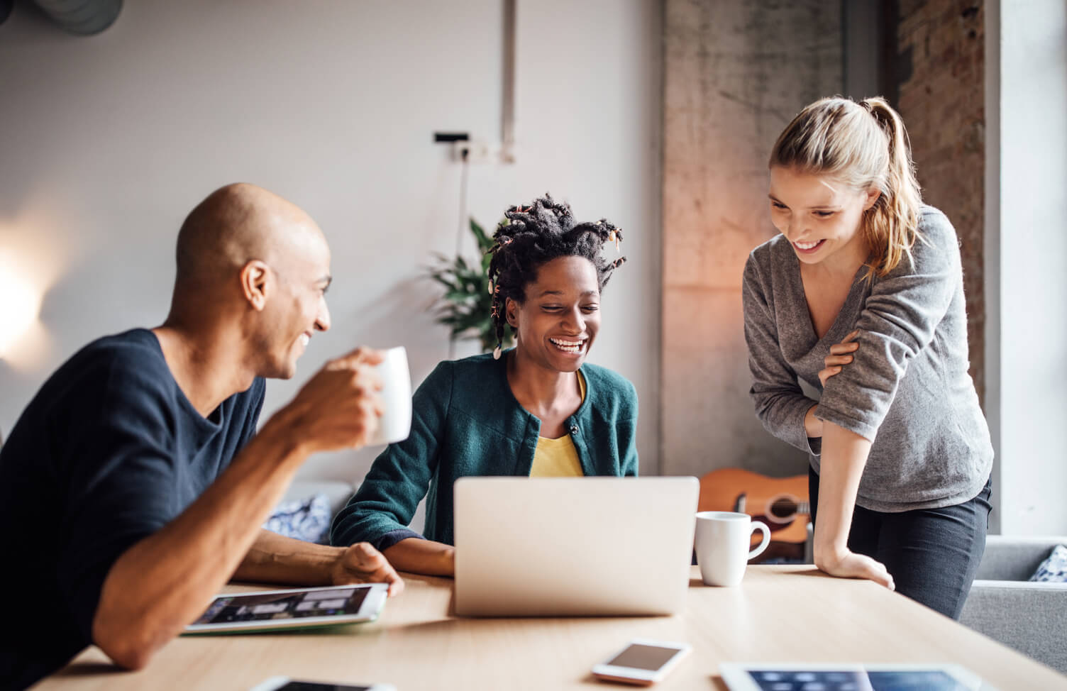 Smiling business people looking at laptop in meeting