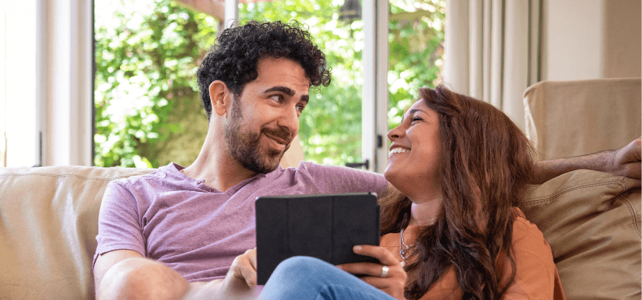 two people smiling at a tablet