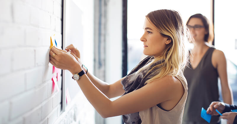 woman putting sticky notes on brick wall