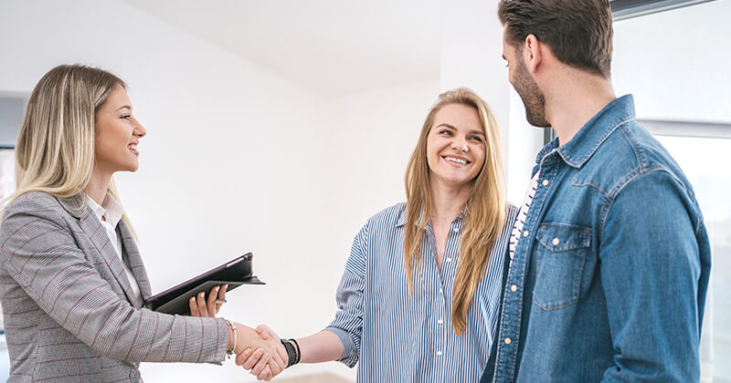 real estate agent shaking hands with new home buyers