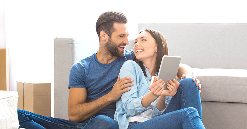 man and woman sitting on couch with tablet
