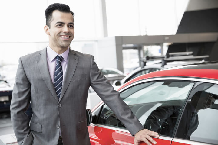 car dealer next to a red car