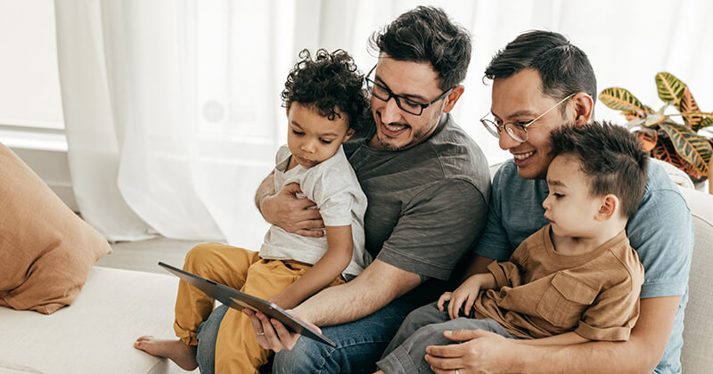 two man with kids looking at tablet